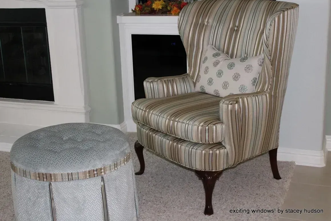 A chair and ottoman in a living room with a fireplace in the background