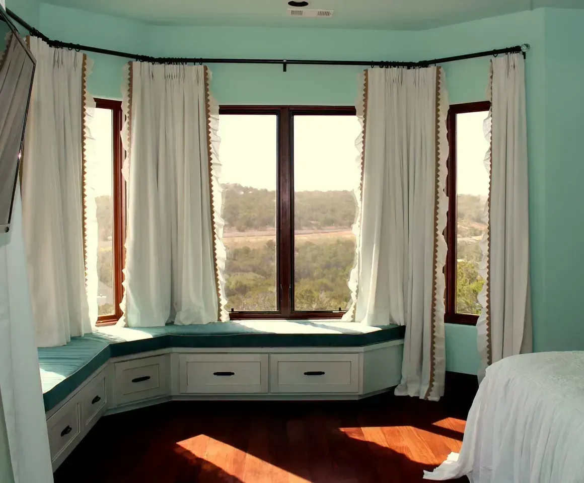 A bedroom with a large bay window and a bed