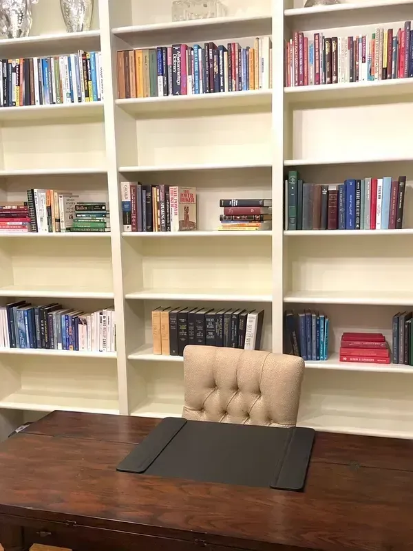 A library with lots of books on shelves and a desk
