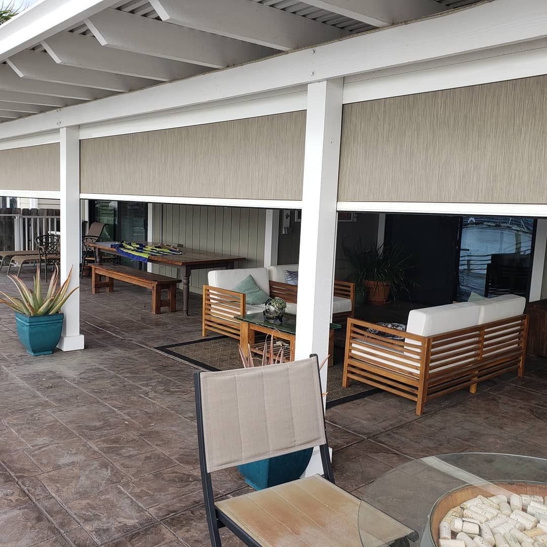 A patio with a couch , chairs , table and potted plants.