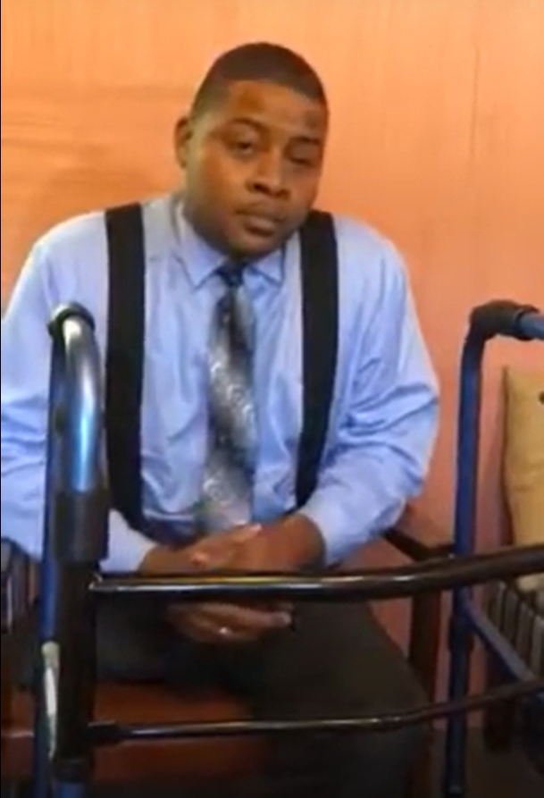 Photo of Nijo Shaw sitting behind his walker, looking as if about to begin telling his story...
