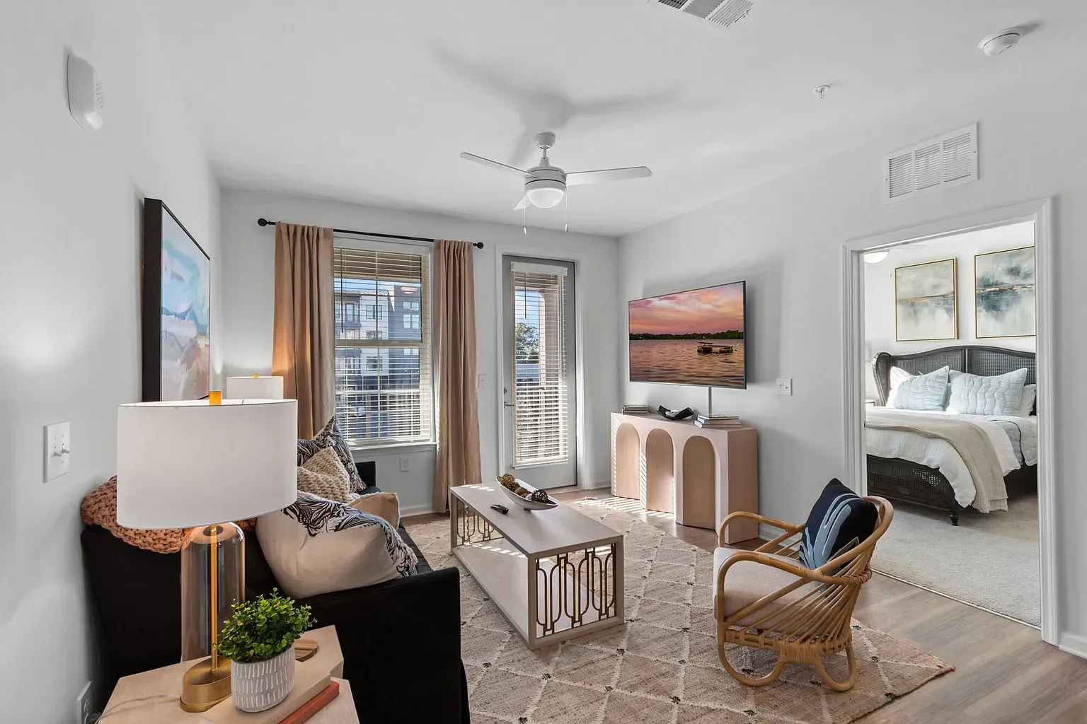 Living room in a modern apartment with sofa, coffee table, TV, and doorway to a bedroom.
