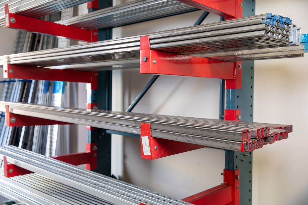 Red cantilever shelves holding metal bars inside a warehouse.