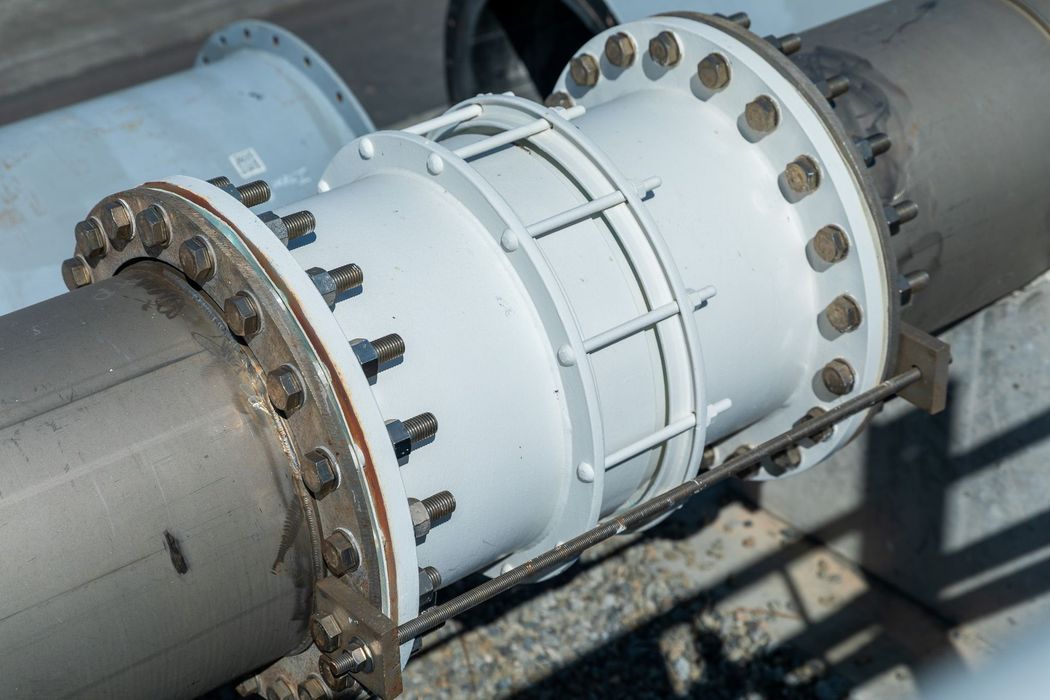 White pipes connected with a large, bolted fitting, part of an industrial system.