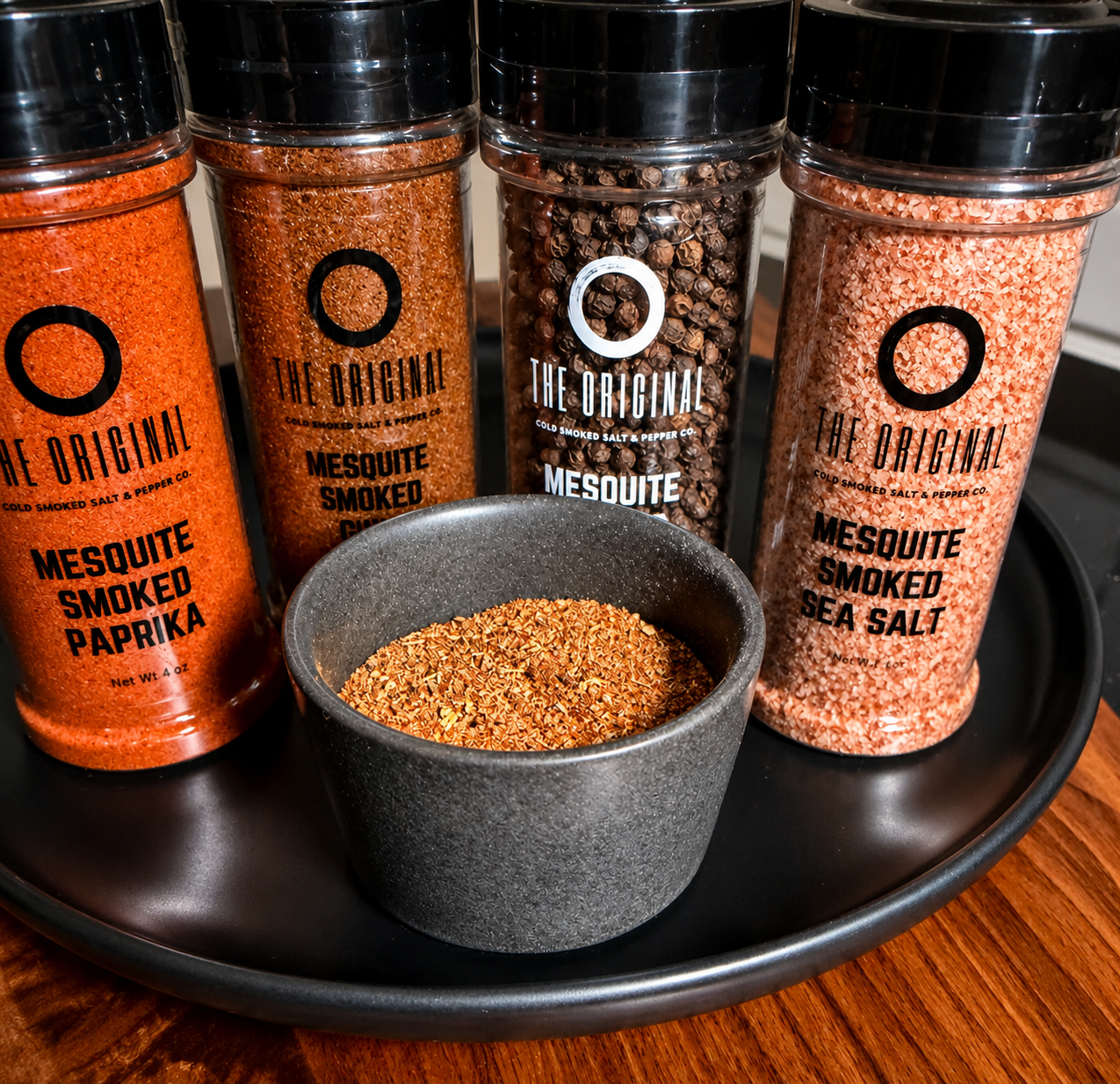 Assorted spice jars on a tray with a small bowl of seasoning in front