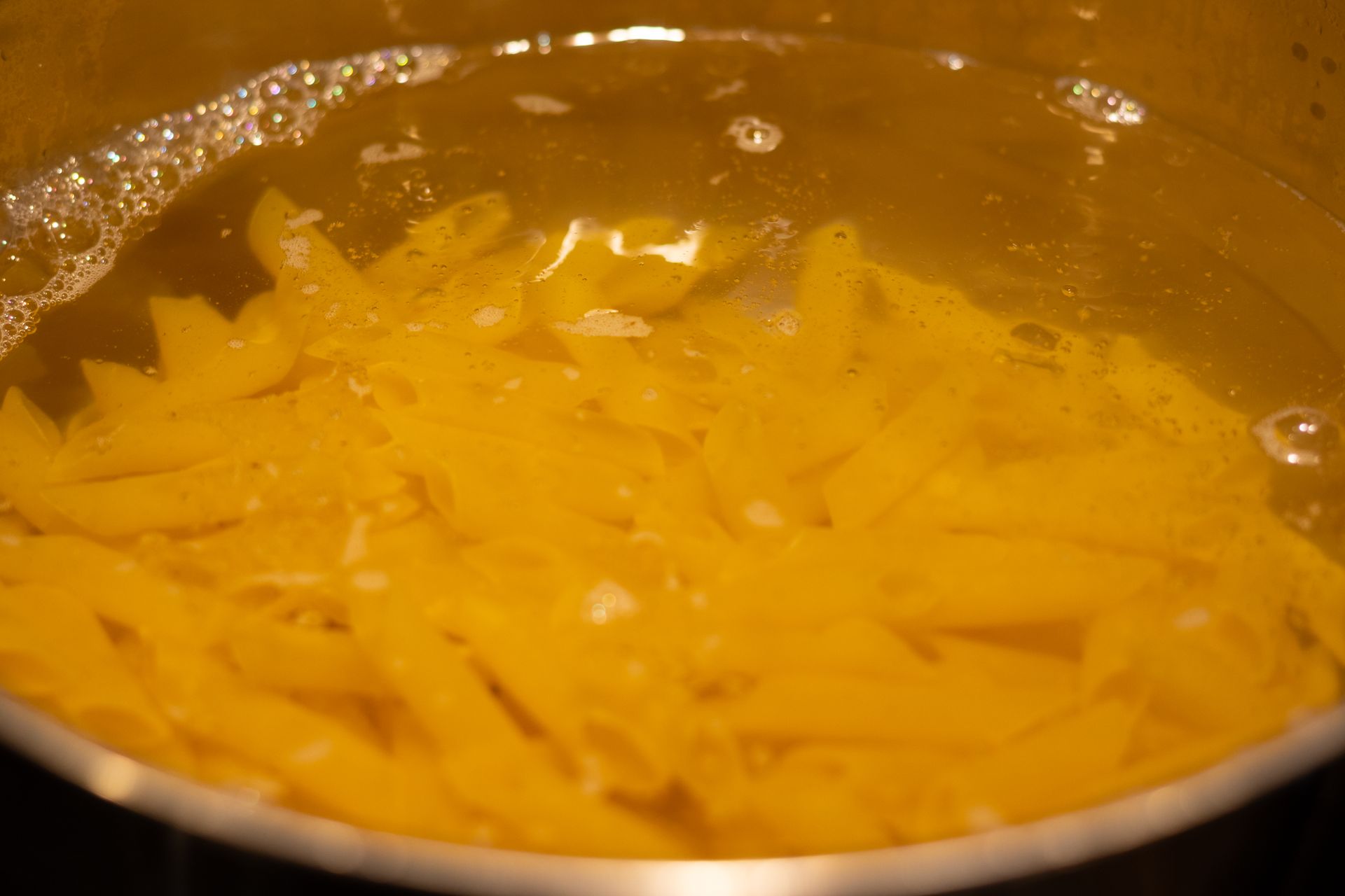 Pasta is being cooked in a pot of boiling water.
