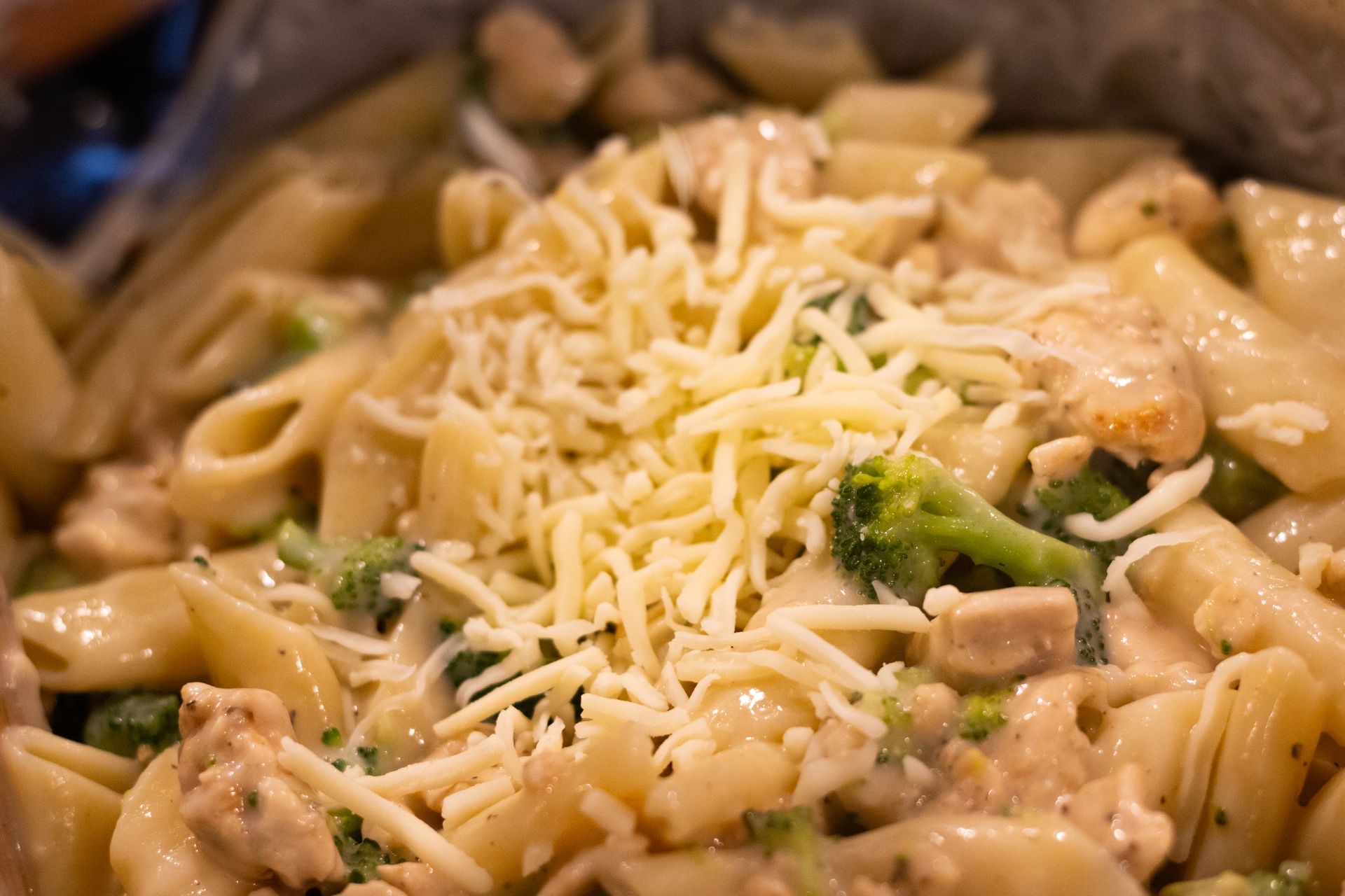 A close up of a pasta dish with broccoli and cheese on top.