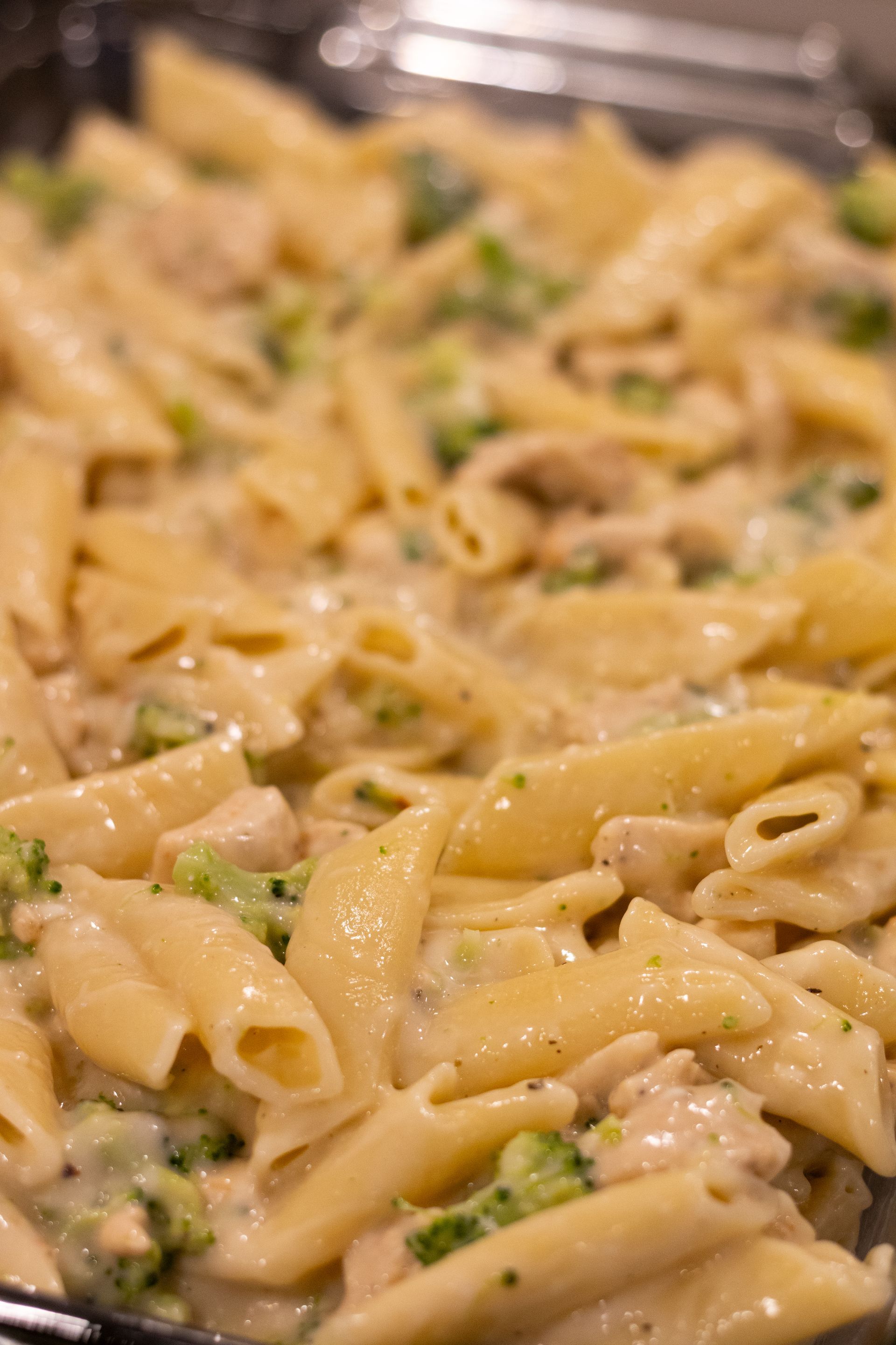 A close up of a pan of pasta with broccoli and chicken.