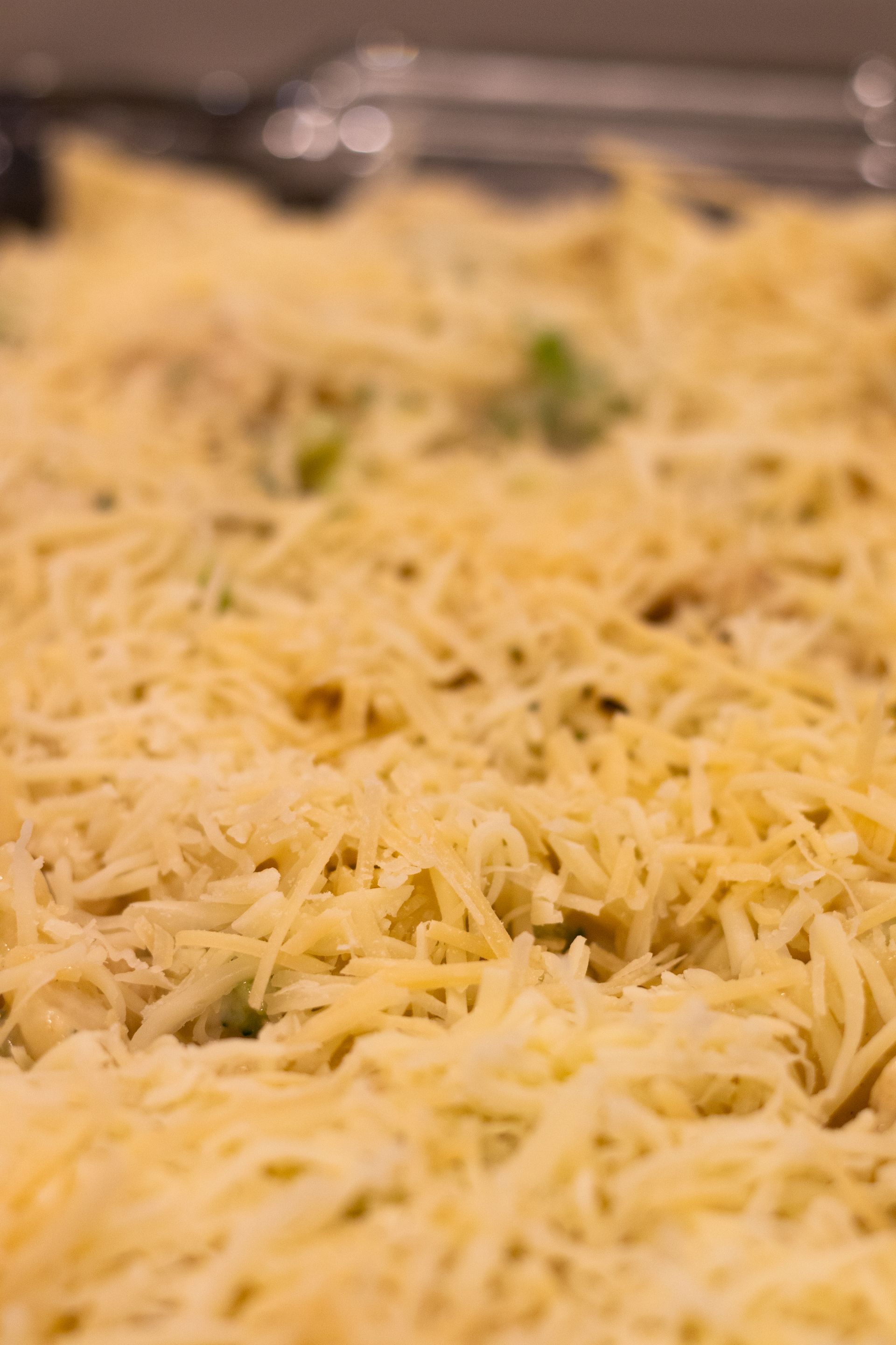 A close up of a casserole dish filled with shredded cheese and vegetables.