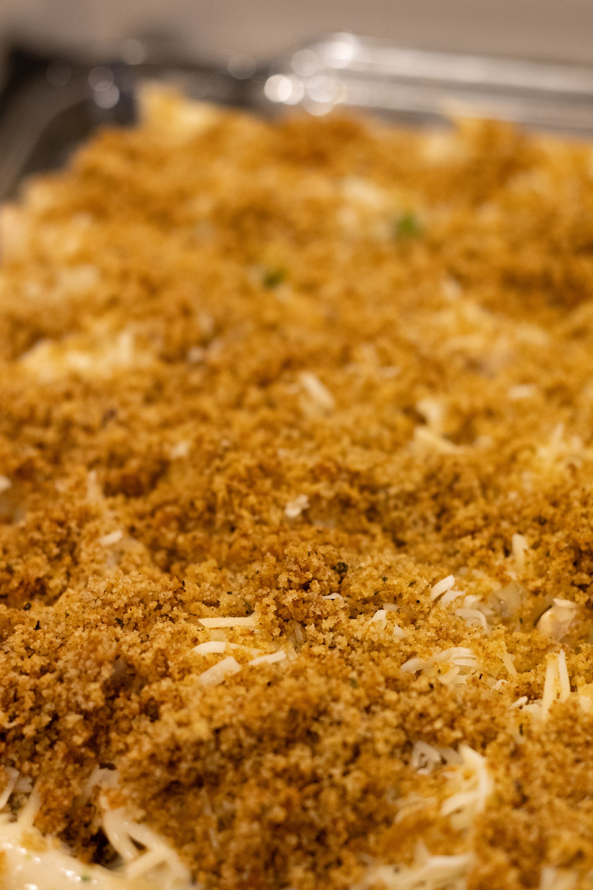 A close up of a casserole dish filled with bread crumbs and cheese.