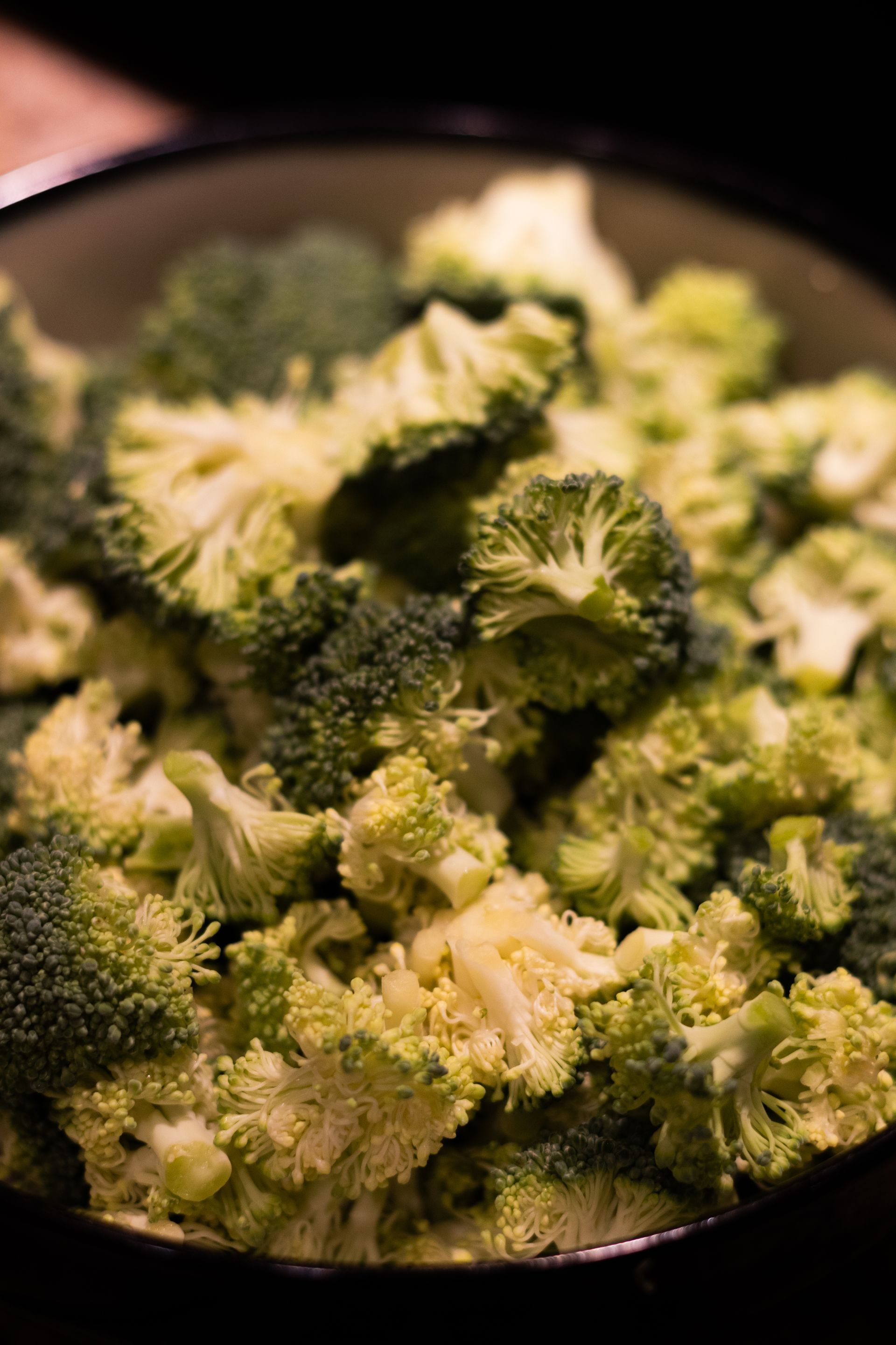 A close up of a bowl of broccoli on a table.