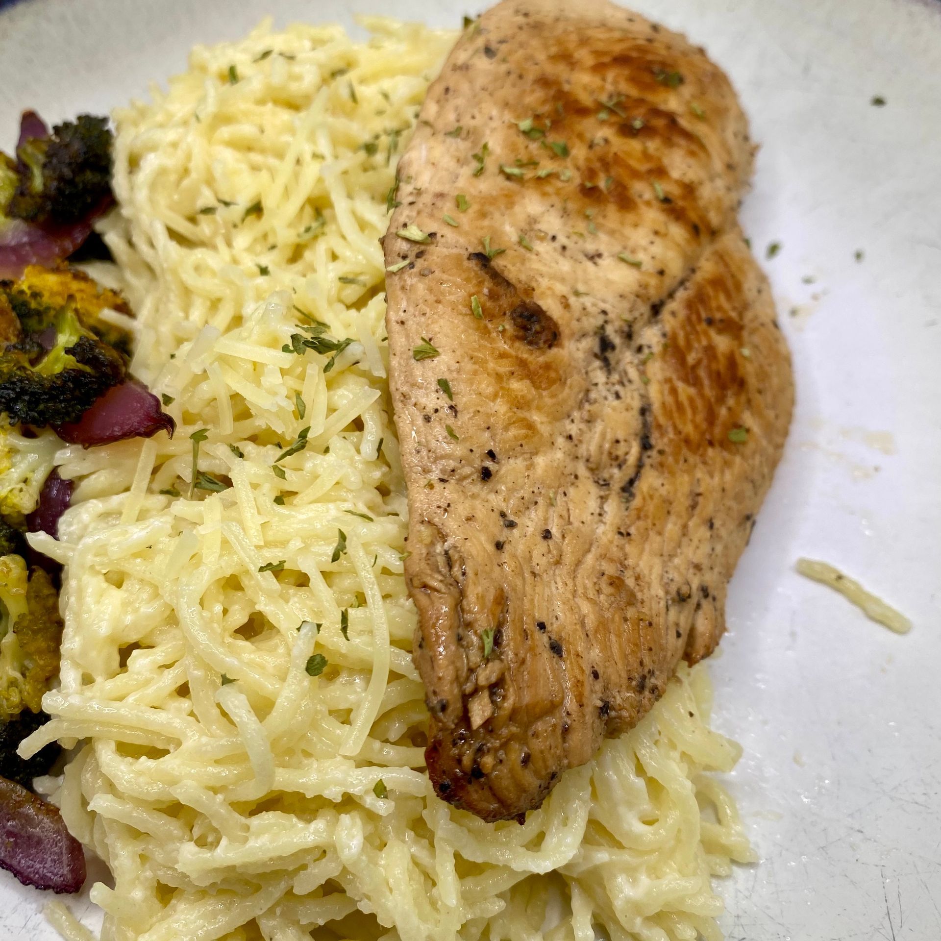 Grilled chicken breast on pasta with roasted vegetables.