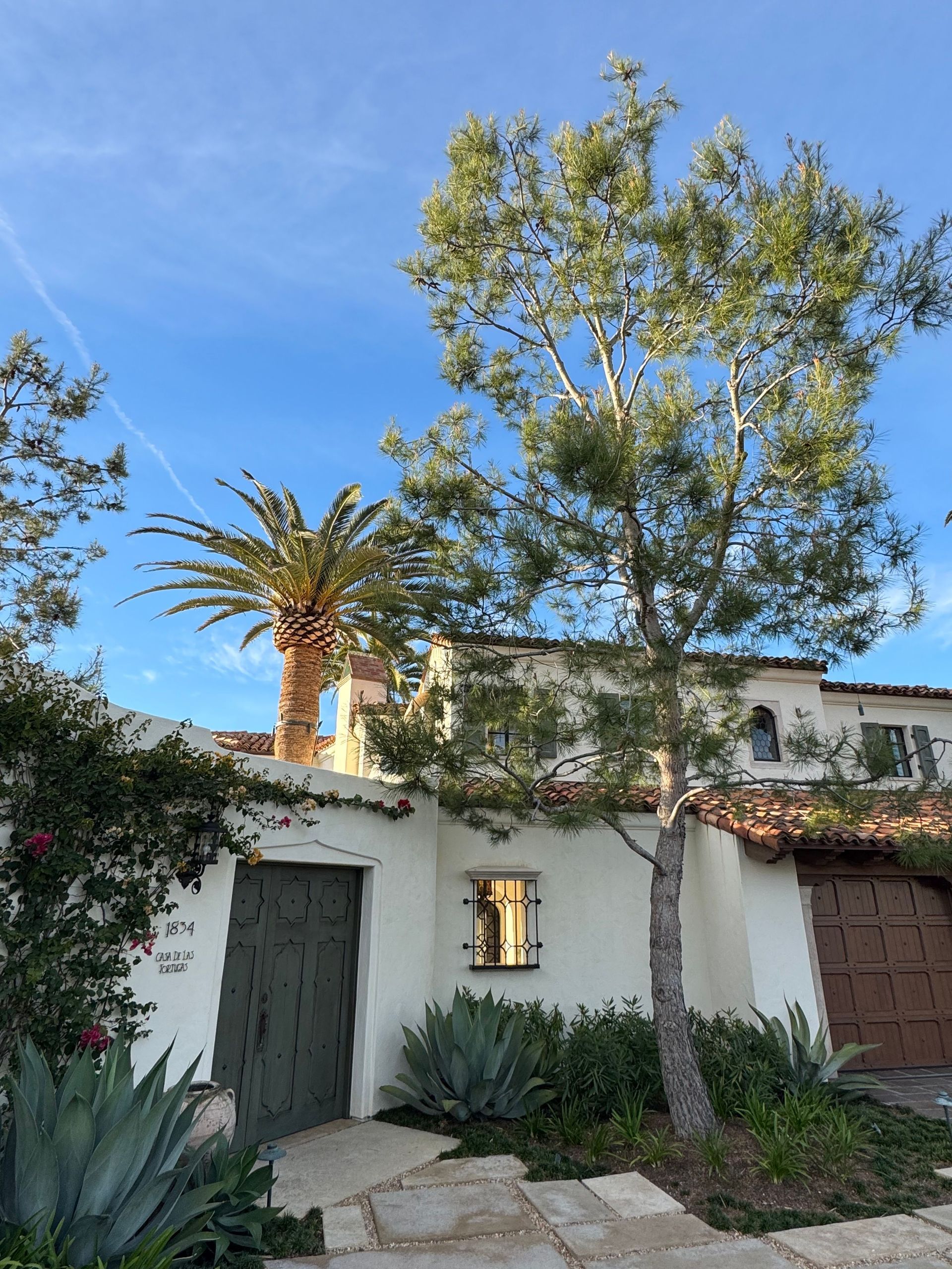 Two workers on an orange lift repairing the exterior of a gray house
