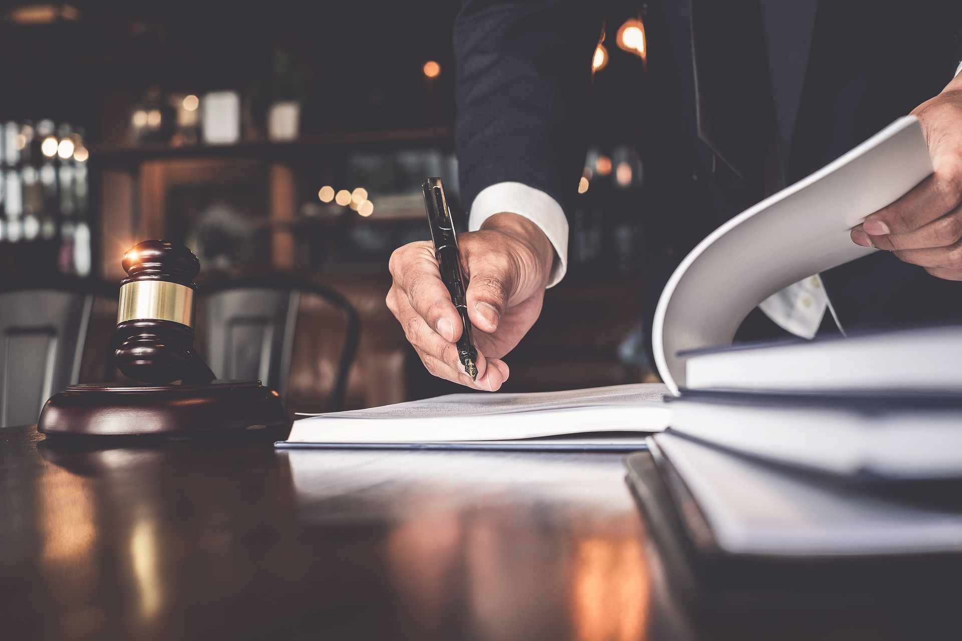 Business professional signing legal contract with pen, gavel and paperwork on office desk scene.