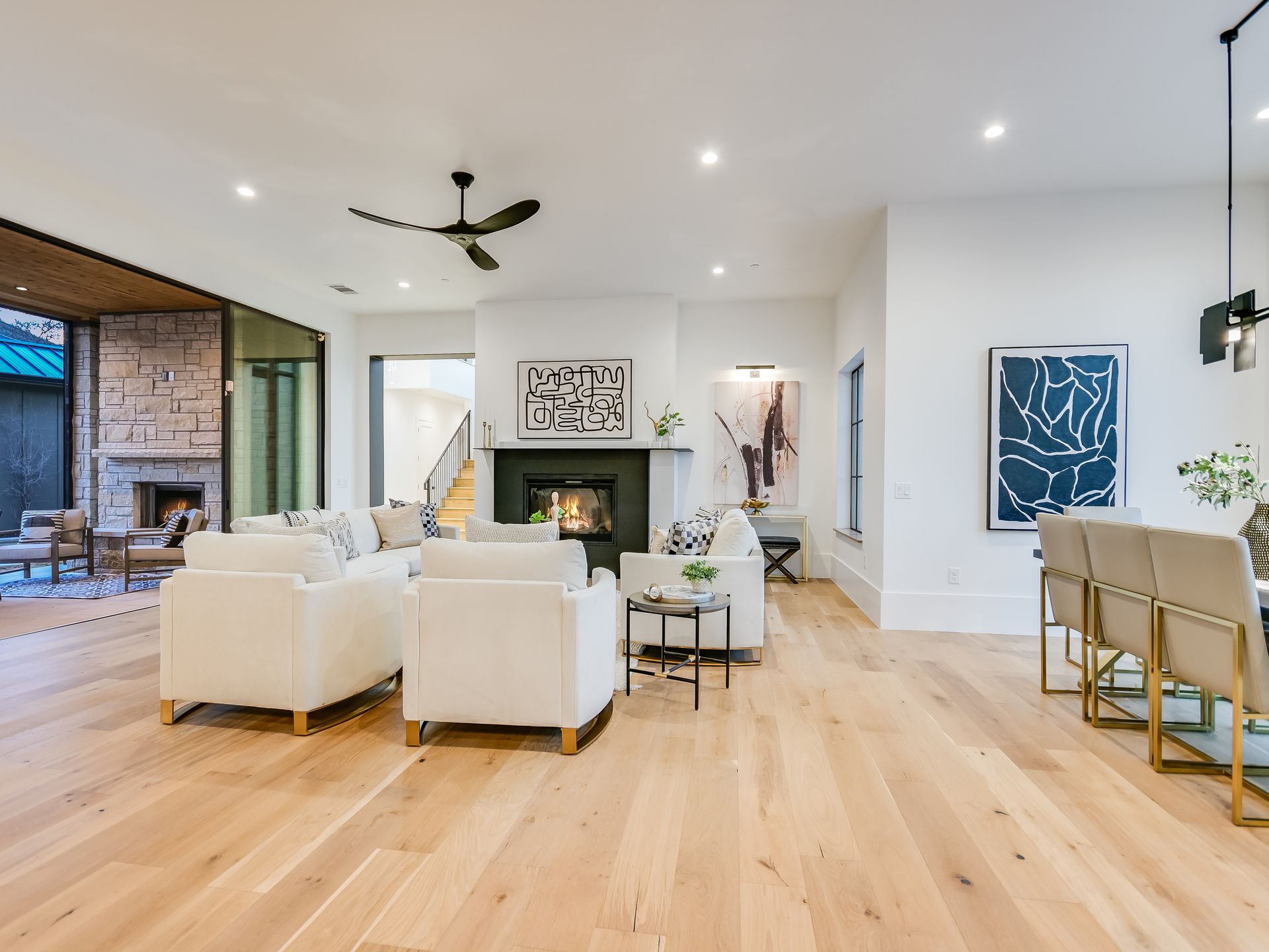 A living room with hardwood floors , white furniture , a fireplace and a ceiling fan.