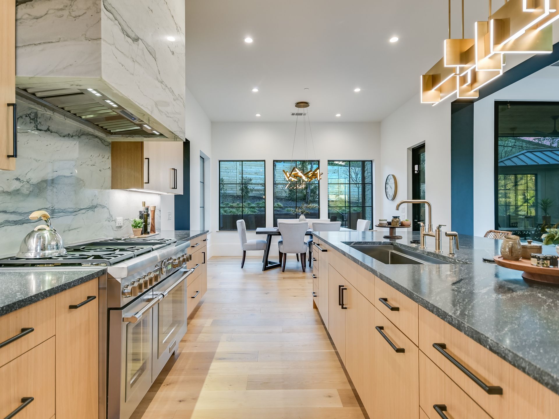 A kitchen with stainless steel appliances , granite counter tops , wooden cabinets and a large island.