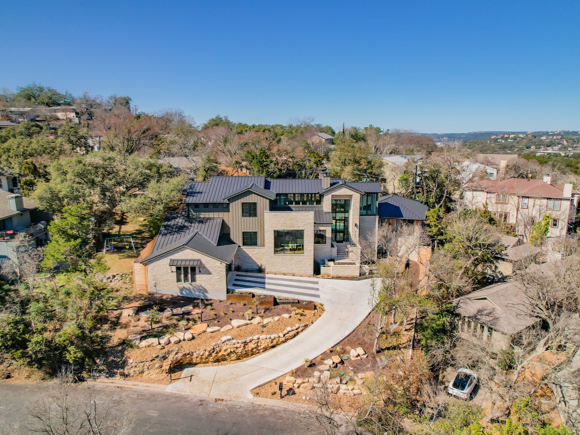 An aerial view of a large house sitting on top of a hill surrounded by trees.