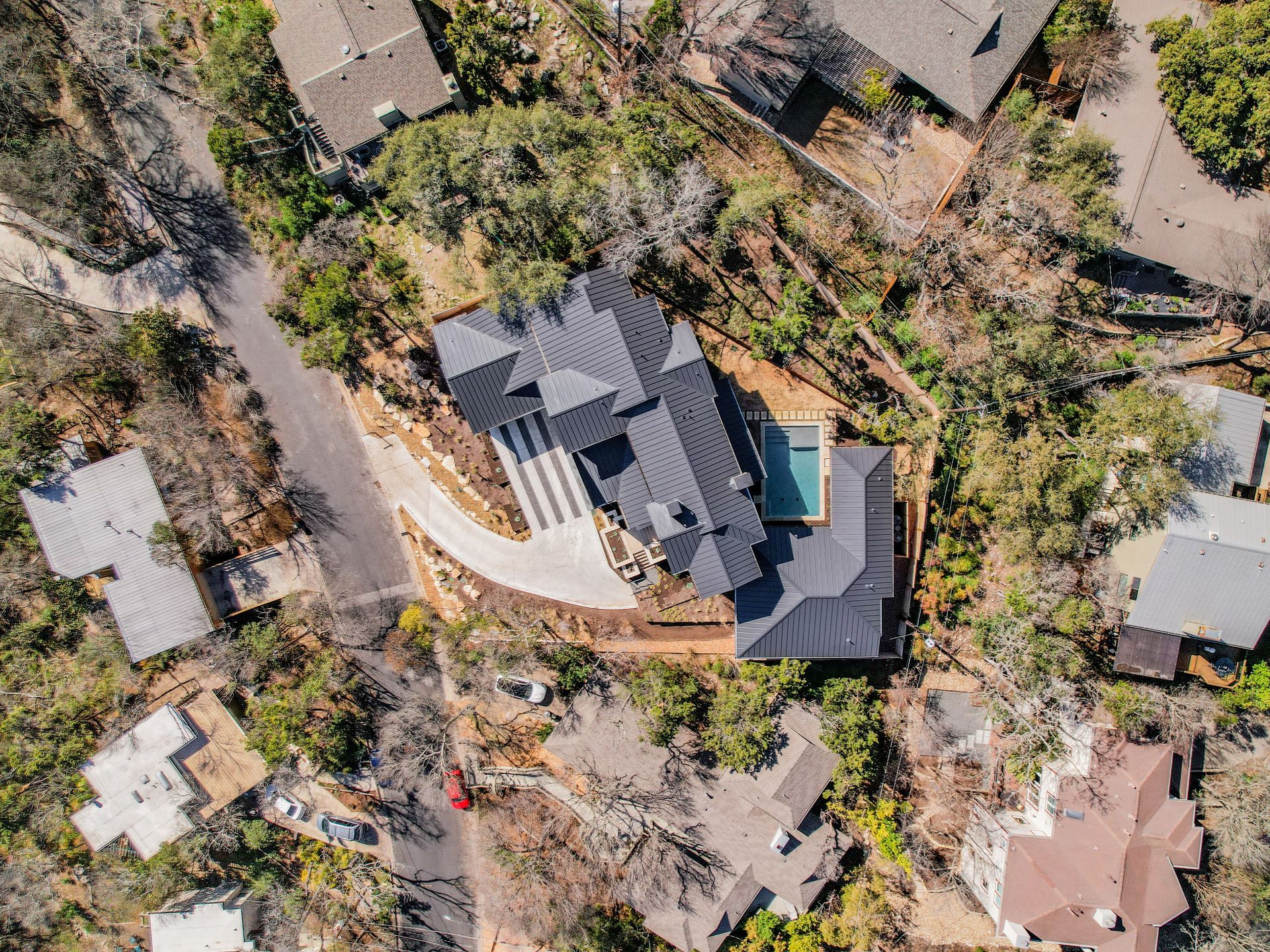 An aerial view of a house on top of a hill surrounded by trees.