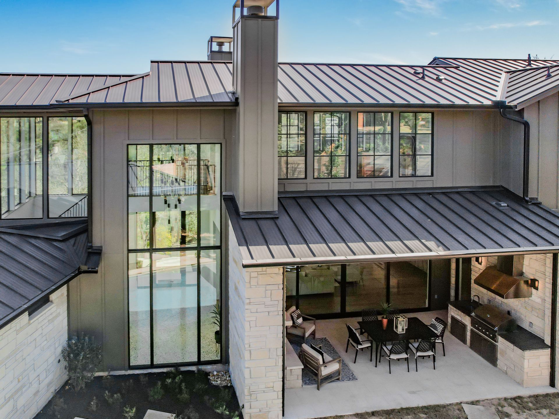 A large house with a metal roof and a patio with a table and chairs.
