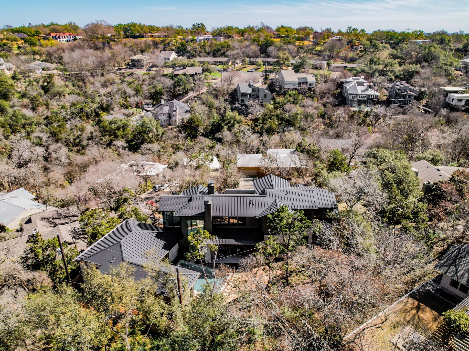 An aerial view of a house surrounded by trees in a residential area.