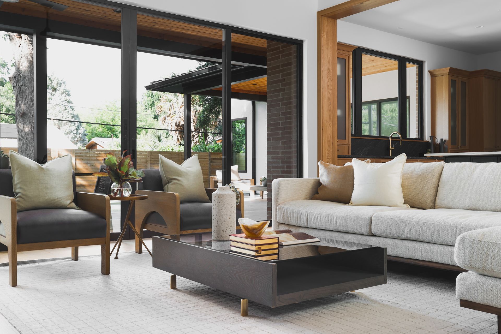 Living room with gray sofa, armchairs, and coffee table; large windows overlook a patio.