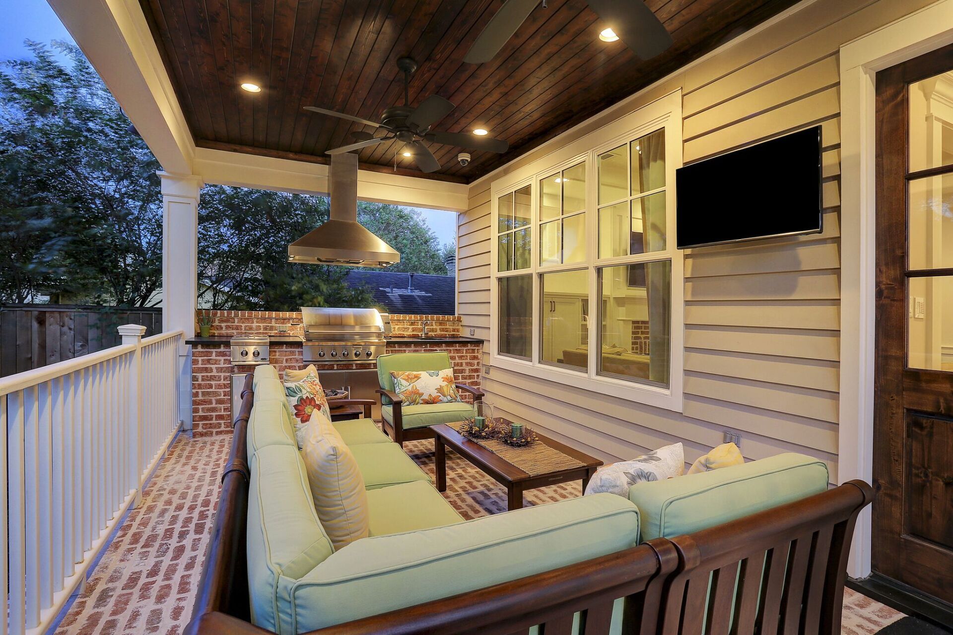 A porch with a couch and a television on the wall.