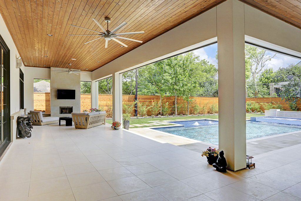 A large patio with a ceiling fan and a swimming pool in the background.