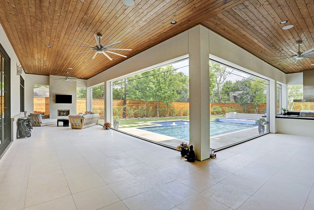 A large room with a ceiling fan and a swimming pool in the background.