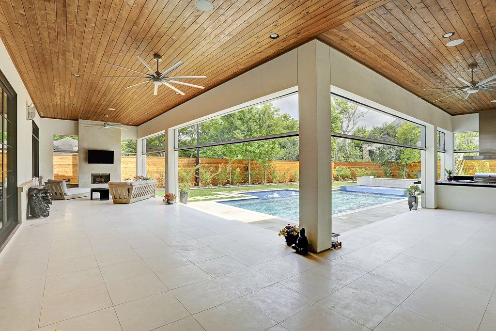 A large patio with a wooden ceiling and a swimming pool in the background.