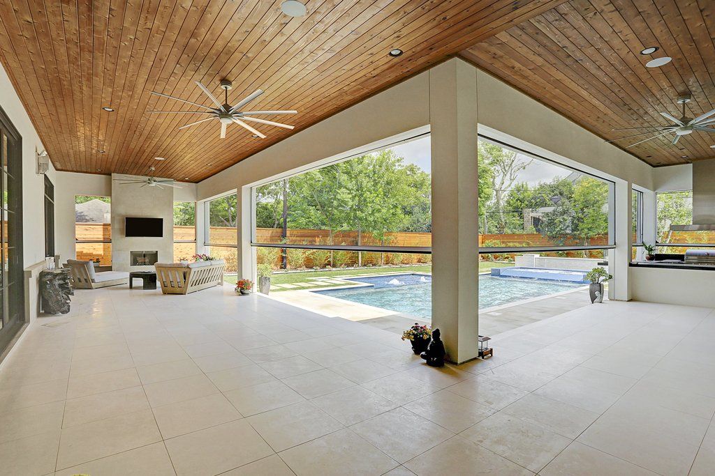 A large patio with a wooden ceiling and a swimming pool in the background.