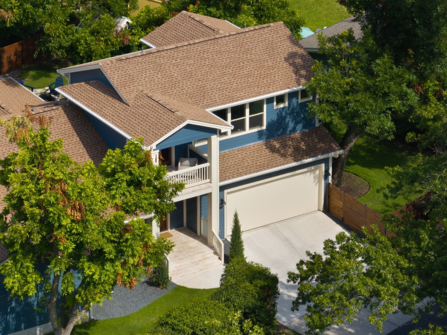 Blue house with white trim, stone wall and walkway, and green lawn under a blue sky.
