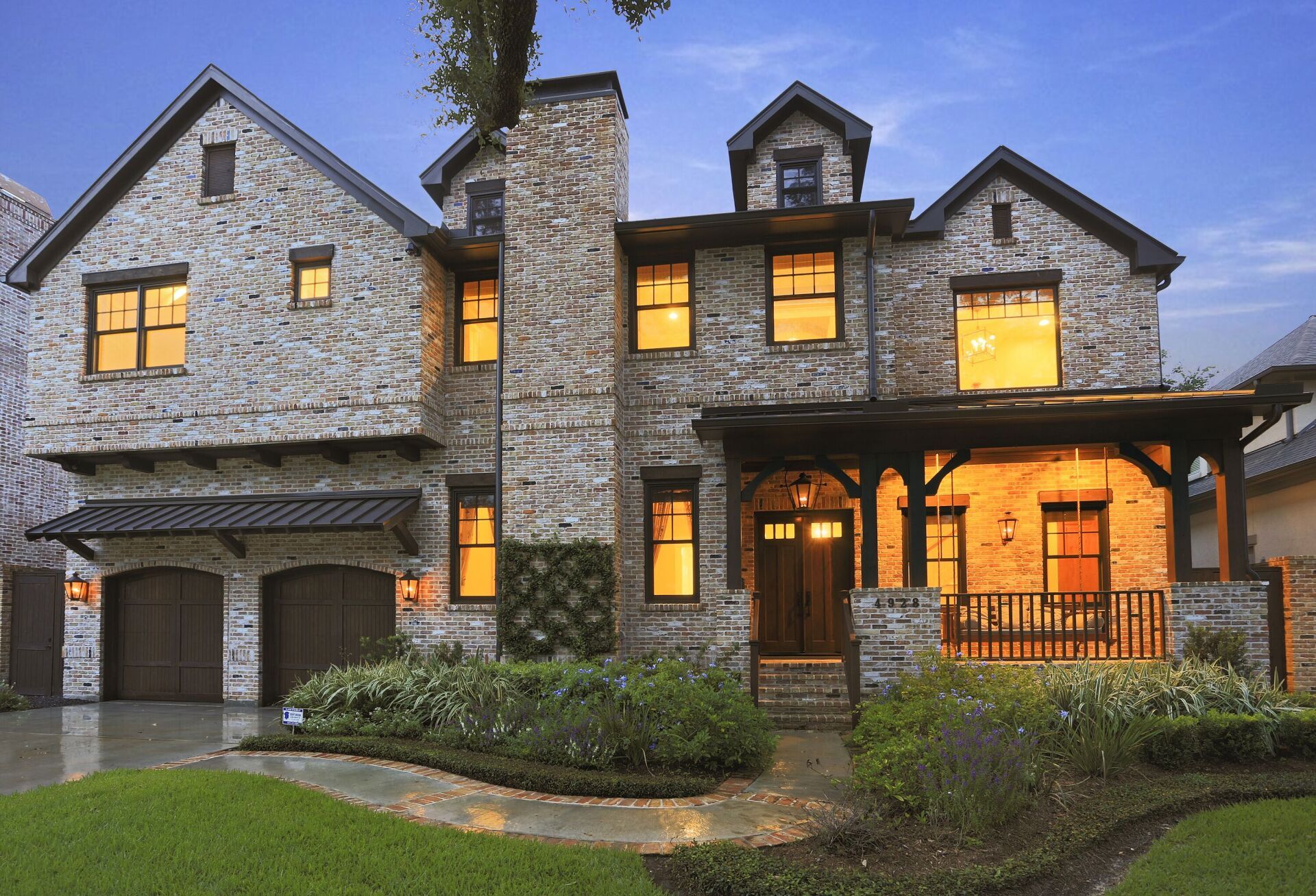 A large stone house with two garages and a porch