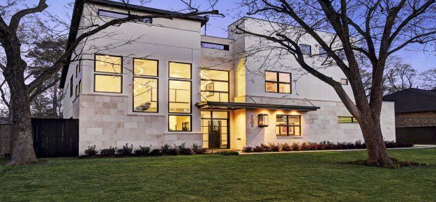 A large white house with lots of windows and trees in front of it.