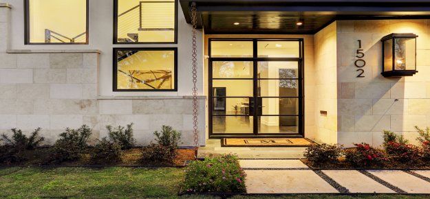 A modern house with a large front door and a walkway leading to it.