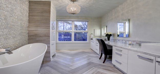 A bathroom with a tub , sink , mirror and window.