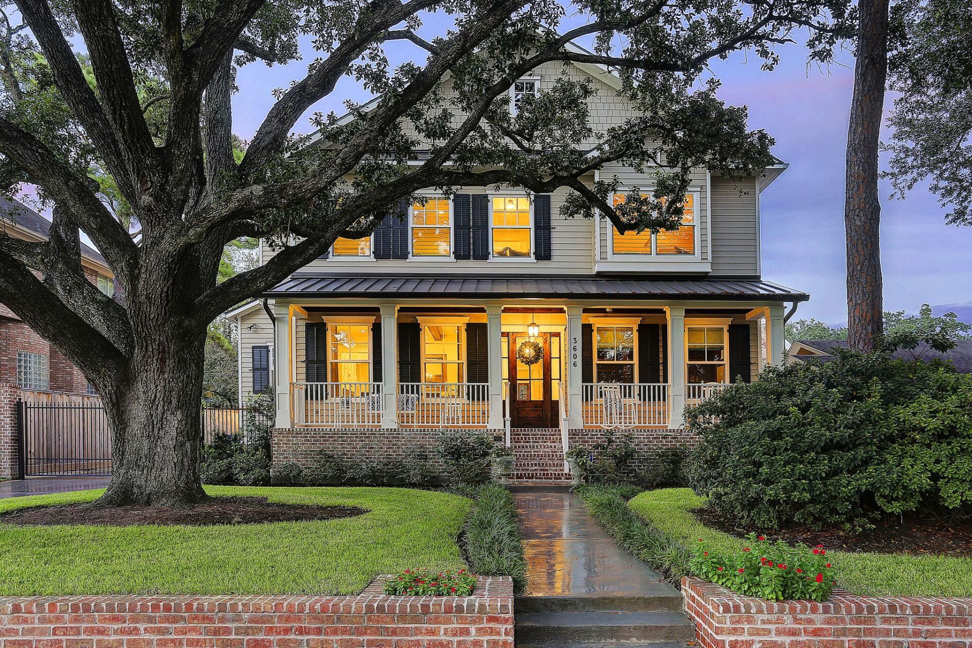A house with a large porch and a tree in front of it