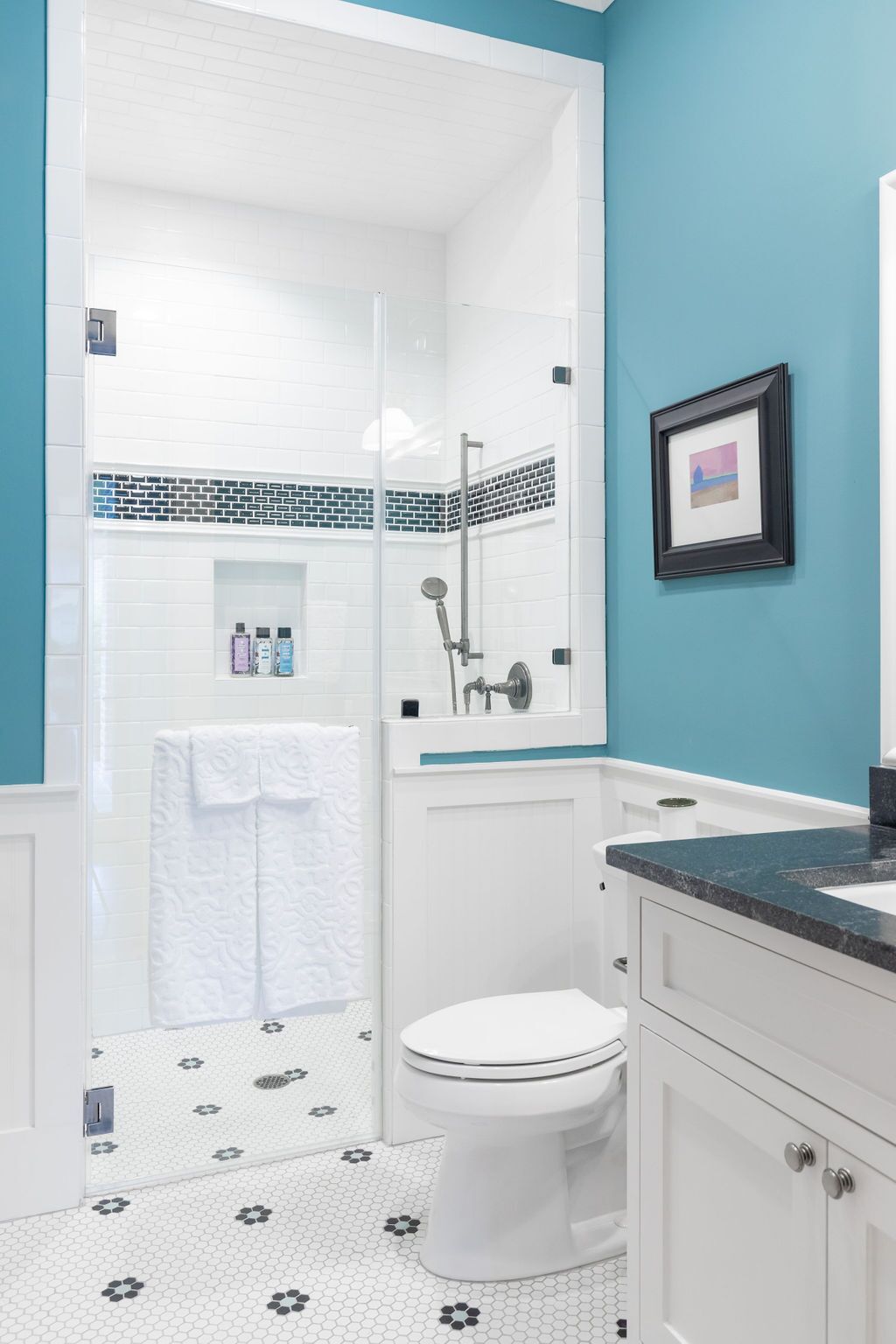A bathroom with a toilet , sink , shower and blue walls.