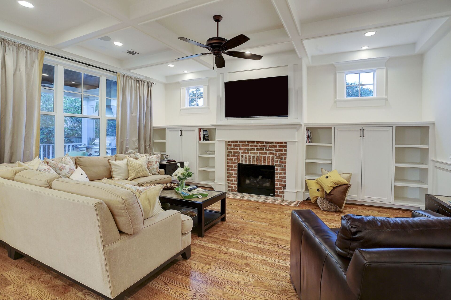 A living room filled with furniture , a fireplace , a flat screen tv and a ceiling fan.