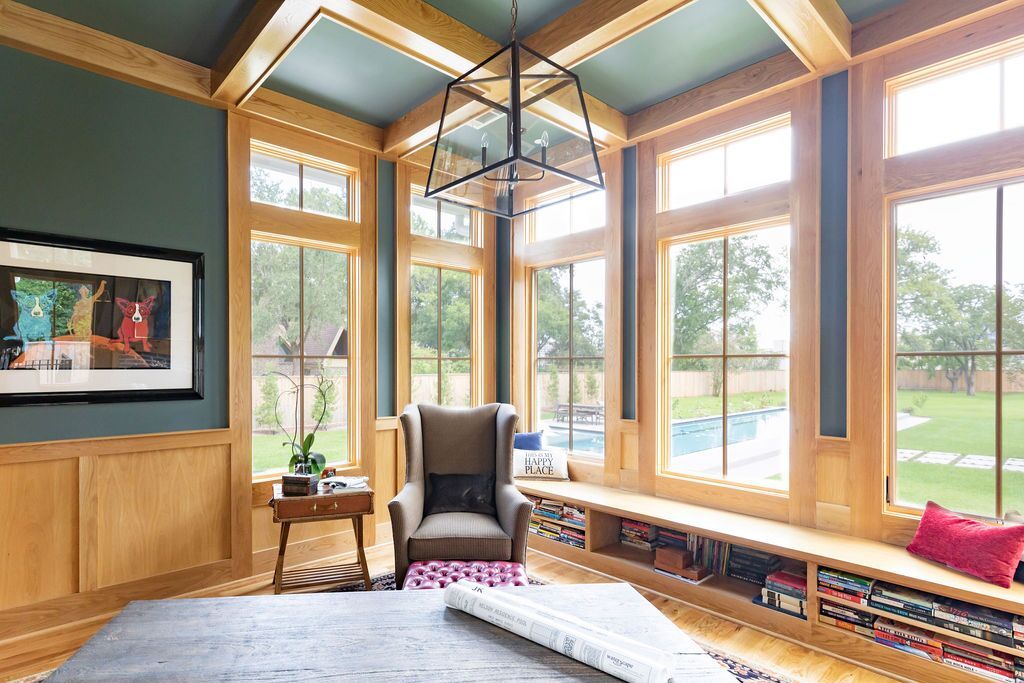 A living room with a lot of windows and a chair.