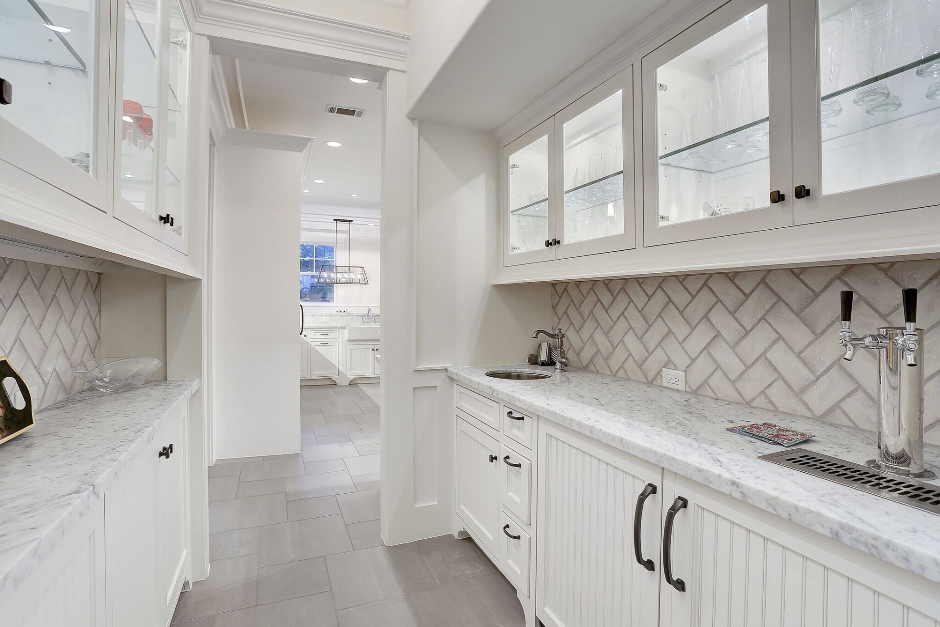 A kitchen with white cabinets and marble counter tops.