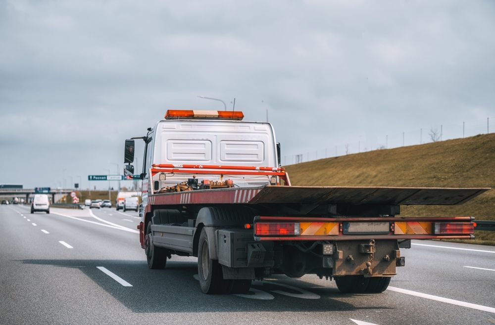 A Tow Truck Is Driving Down A Highway With A Flat Bed — Venus Couriers Pty Ltd In Mackay, QLD