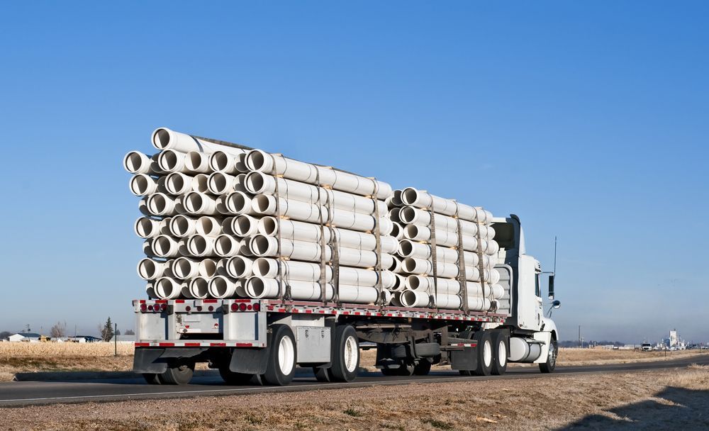 A Semi Truck Is Carrying A Stack Of Pipes On The Back Of It — Venus Couriers Pty Ltd In Mackay, QLD