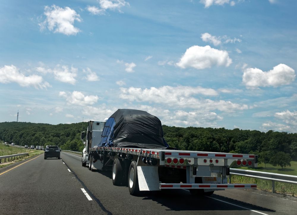 A Flatbed Truck Is Driving Down A Highway — Venus Couriers Pty Ltd In Mackay, QLD
