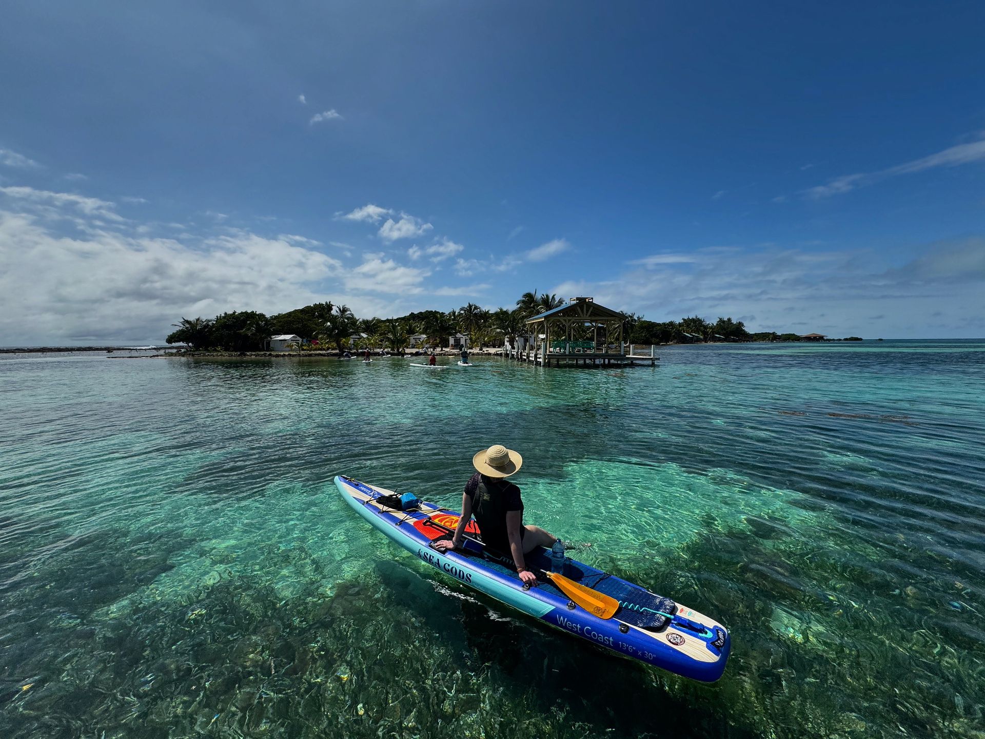 Person paddling a blue kayak on clear turquoise water near a small tropical island