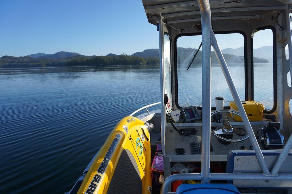 Yellow inflatable boat on calm lake beside a covered dock, with mountains in the distance.