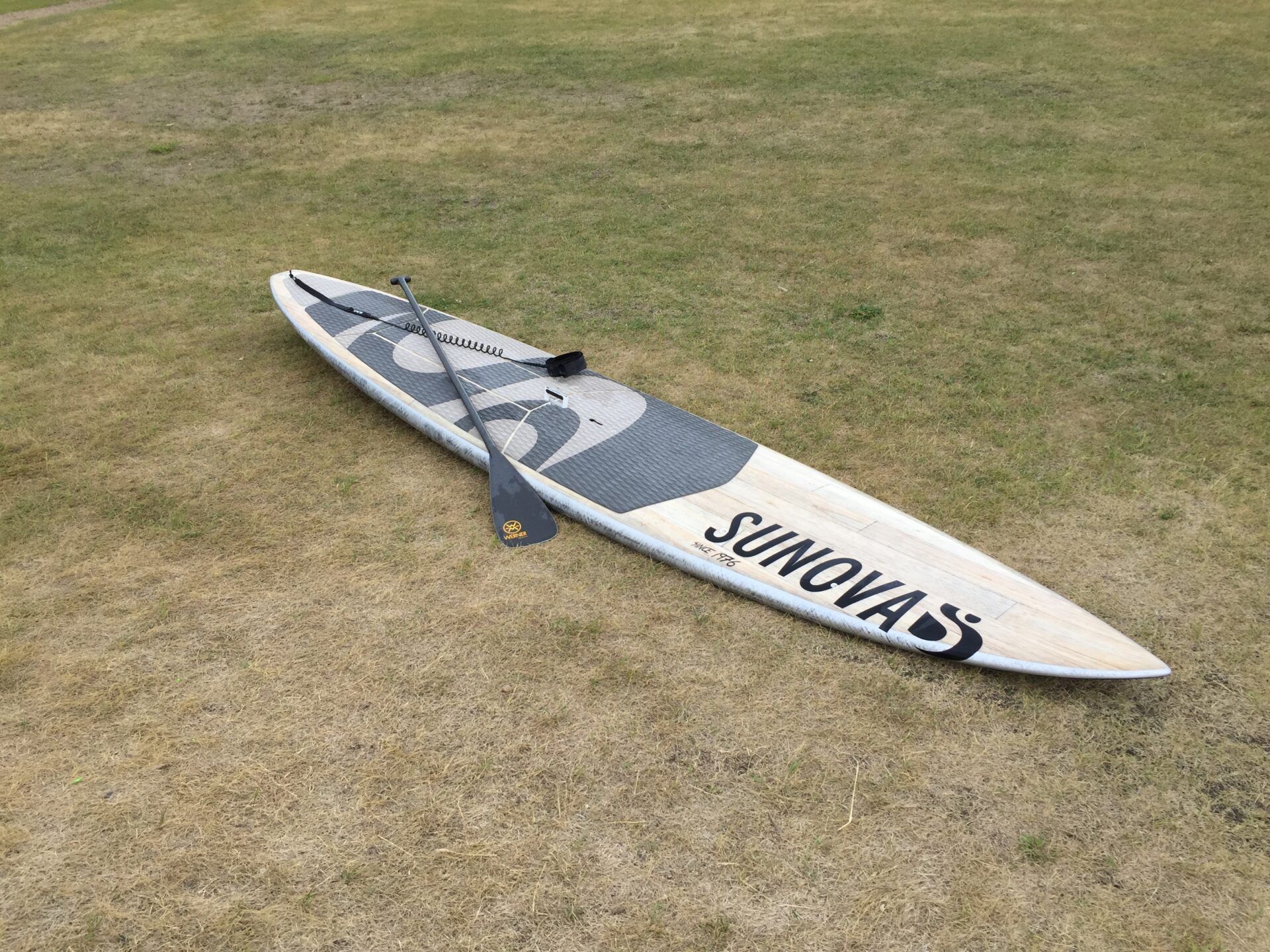 White surfboard with blue/gray deck on dry grass, with “SAYONARA” text visible.