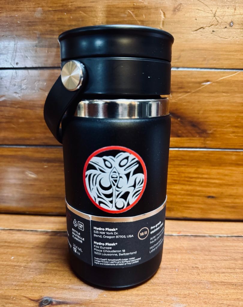 Black insulated bottle with a silver cap and red-and-white circular logo on a wooden surface