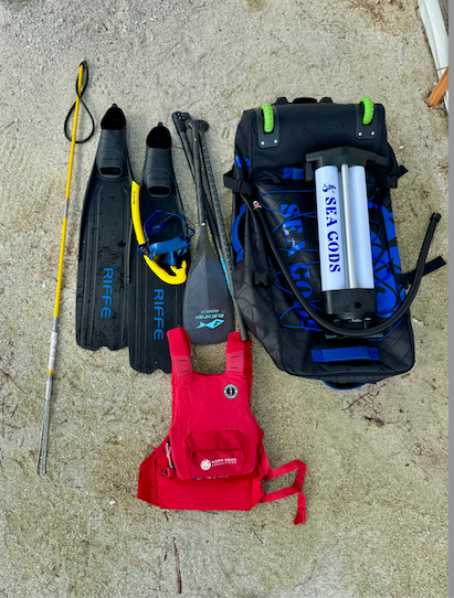 Four folded rescue gear items on concrete: black, red, and blue bags with straps and labels.