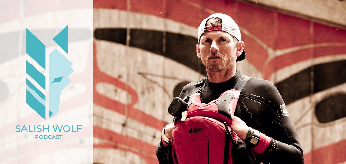 Saul Wolfe, in a red cap and black jacket, holding a red backpack against a graffiti wall.