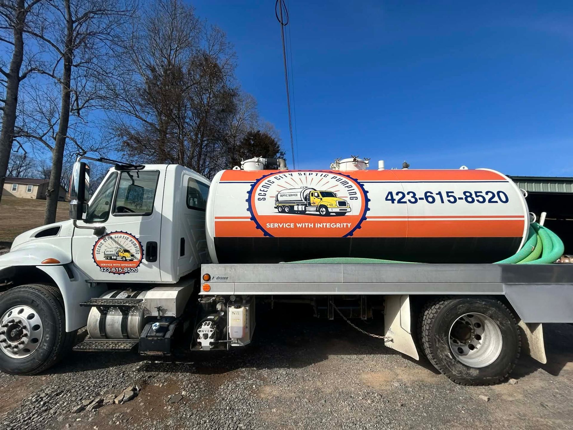 Orange-and-white tanker truck parked outdoors with phone number 423-615-8520 on the tank.